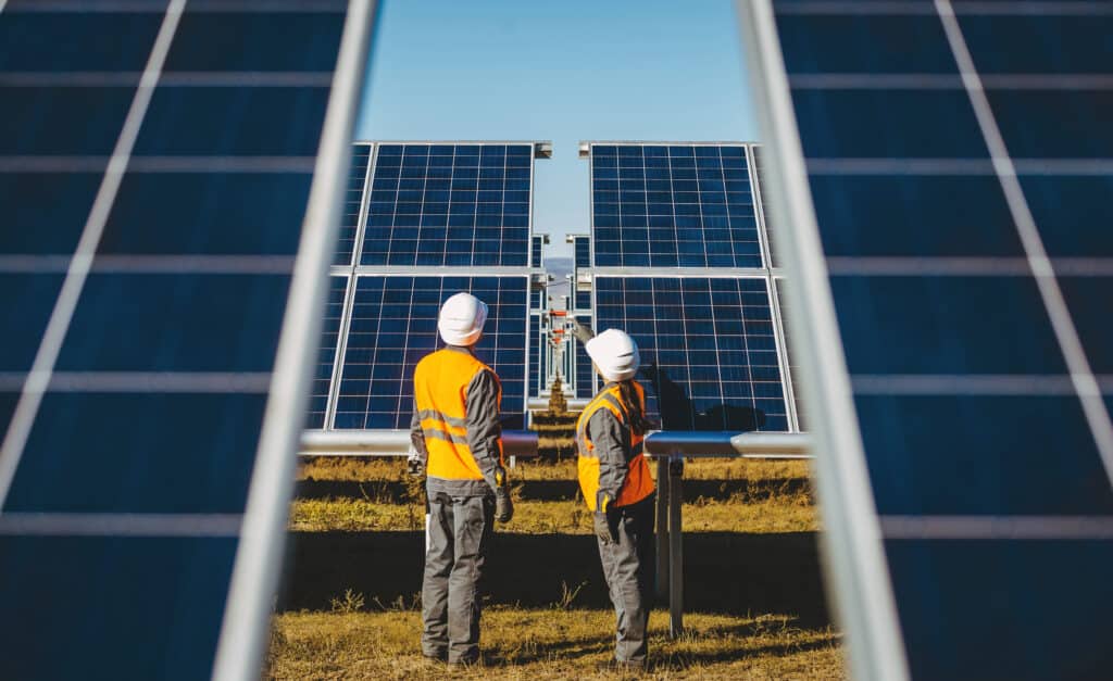 Solar panel experts inspecting panels on a solar farm.